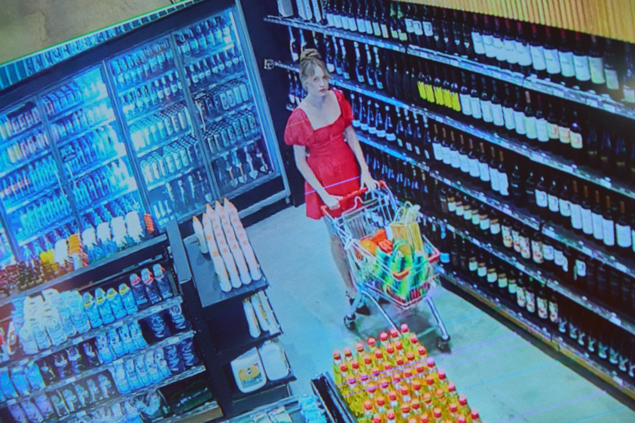 Security-camera view of a shopper pushing a cart down a store aisle